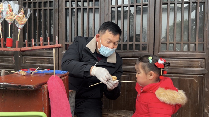 糖画师傅正在给小朋友制作糖人。孟莹摄