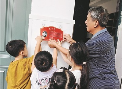 蒋贤礼烈士的儿子蒋义生，与楂林小学“贤礼班”学生一起挂“英烈牌”。季俊磊摄