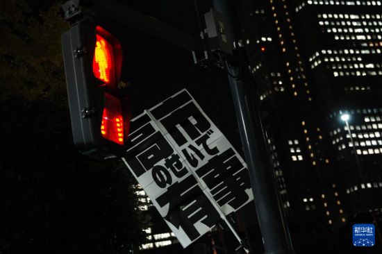 11月21日，在日本东京的首相官邸外，民众举起标语参加抗议活动。新华社记者 贾浩成 摄